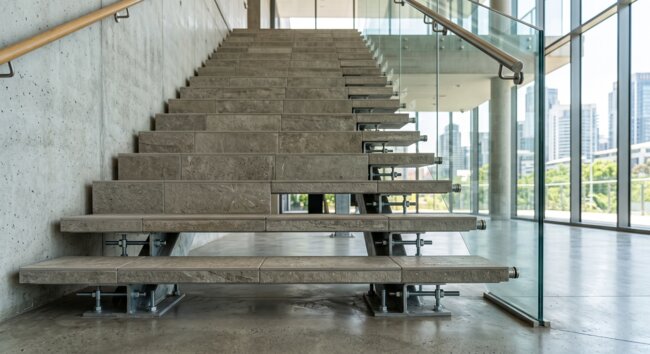 Nowoczesne kamienne schody i szklana balustrada we wnętrzu industrialnym