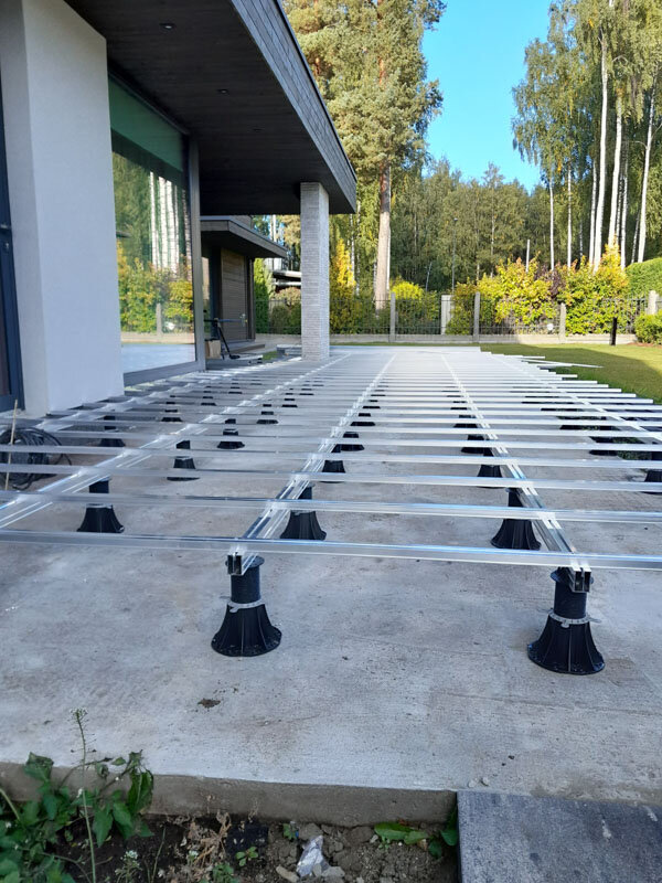 Duża aluminiowa podkonstrukcja legarowa wsparta na regulowanych plastikowych wspornikach na betonowym podłożu tarasowym