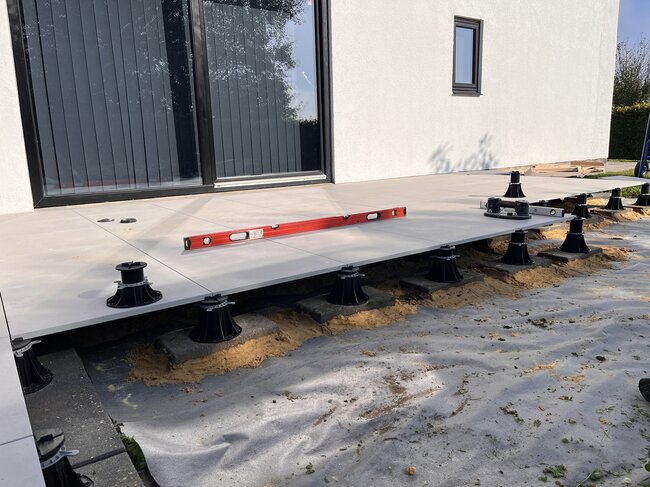 Instalacja podwyższonych płytek tarasowych zewnętrznych przy użyciu regulowanych wsporników tarasowych.