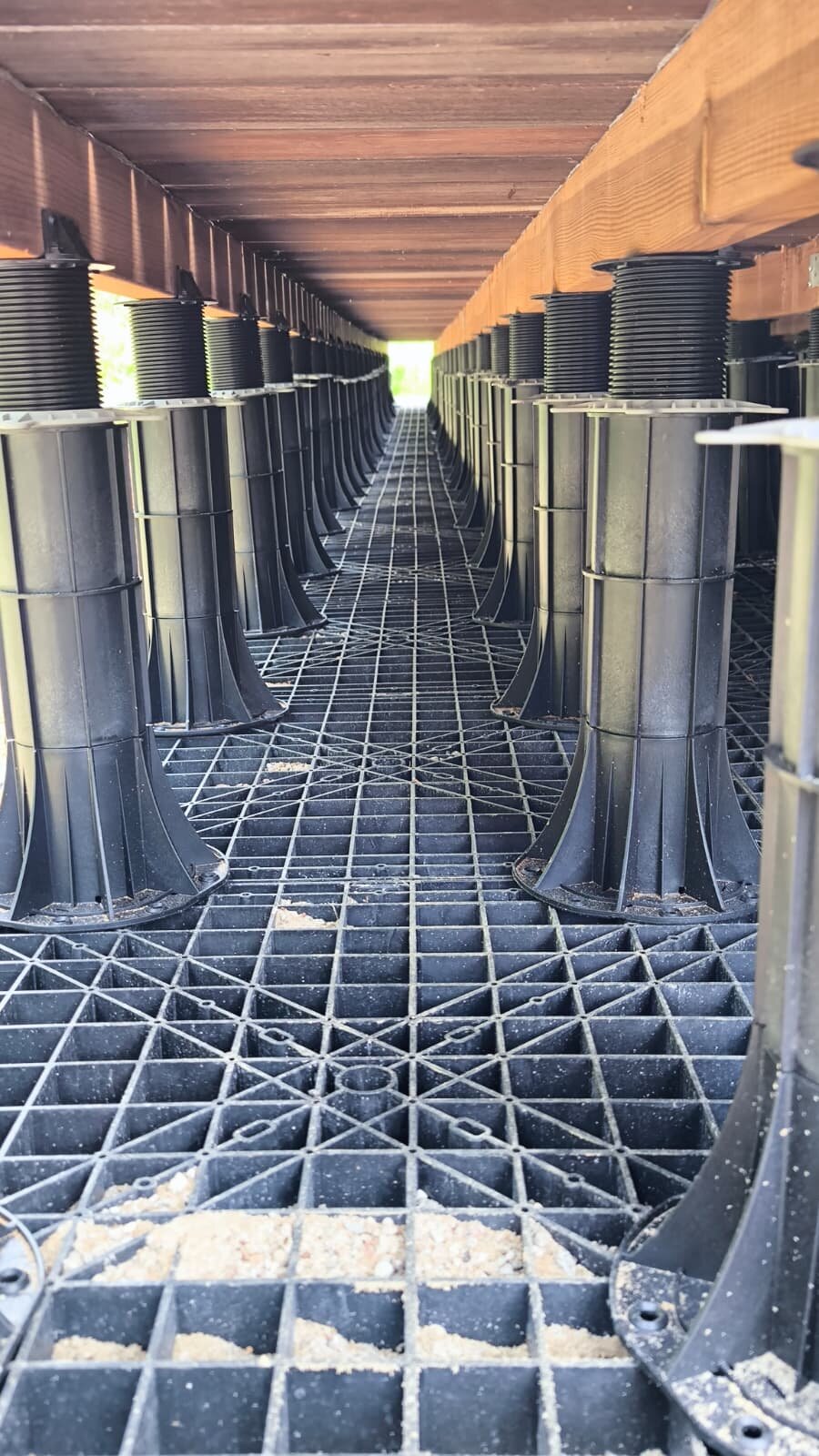Regulowany system wsporników z tworzywa sztucznego zainstalowany pod konstrukcją tarasu na dachu.