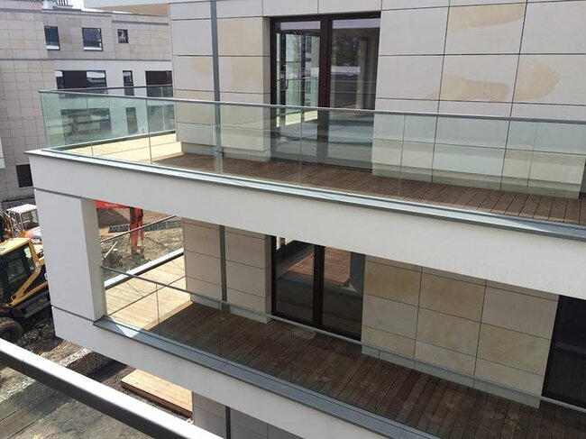 Modern apartment building balconies with wooden decking and glass railings.