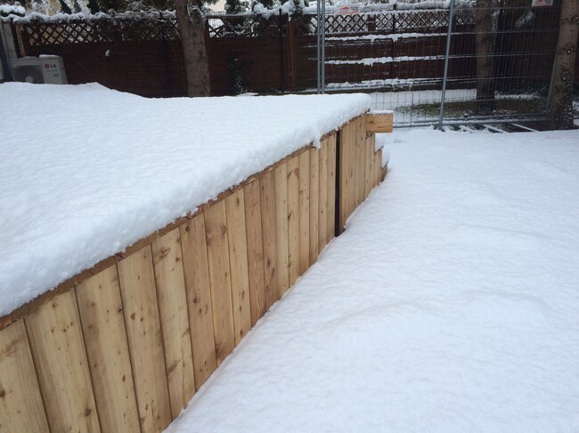 a snow covered wooden deck platform with side cladding outdo