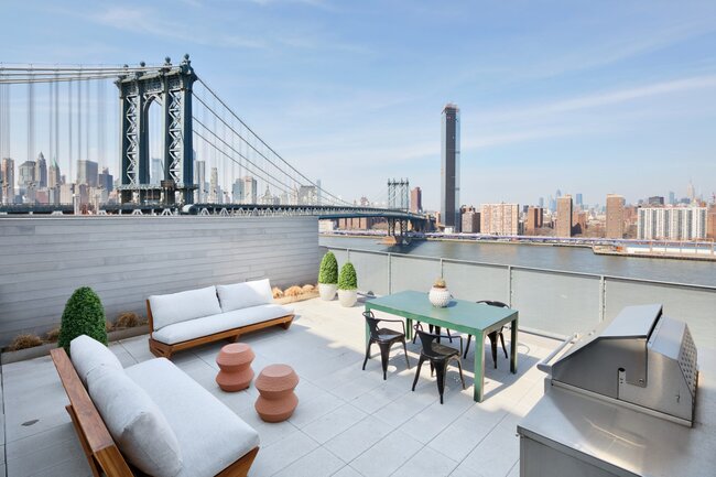 Taras na dachu z meblami ogrodowymi, grillem i widokiem na Manhattan Bridge oraz panoramę Nowego Jorku.