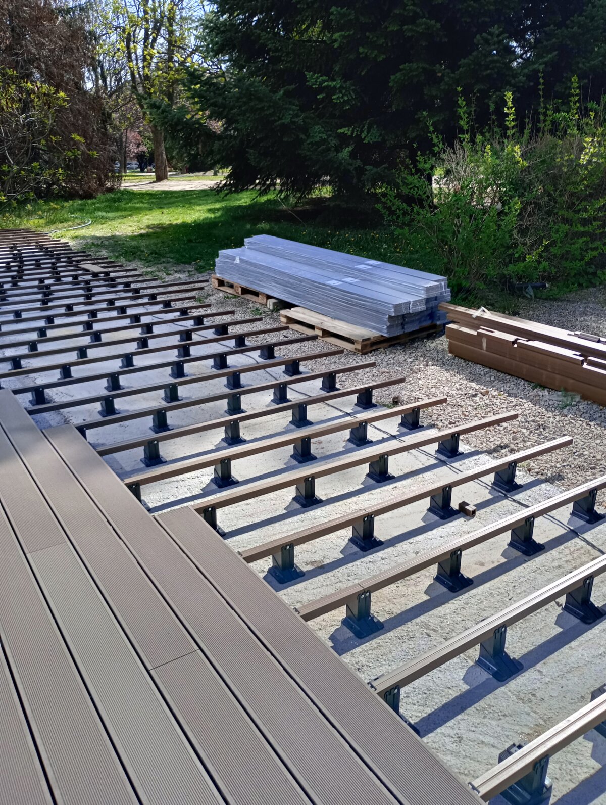 Deski kompozytowe tarasowe montowane na legarach aluminiowych wspartych na regulowanych wspornikach.