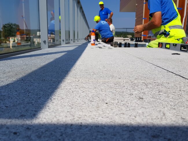 construction workers installing raised terrace pavers on an