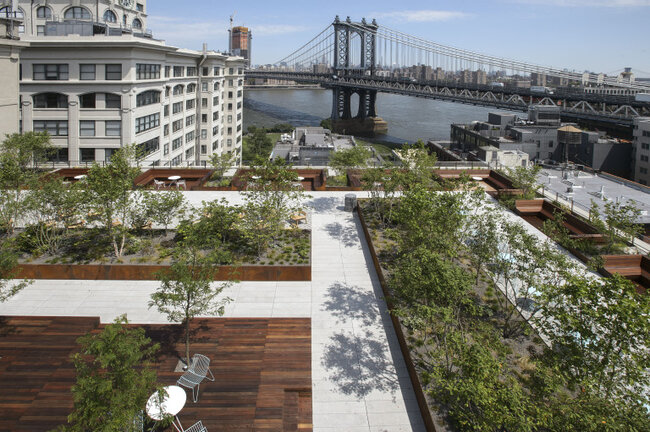 Urban rooftop terrace featuring elevated wood decking and stone paver flooring supported by adjustable pedestals.