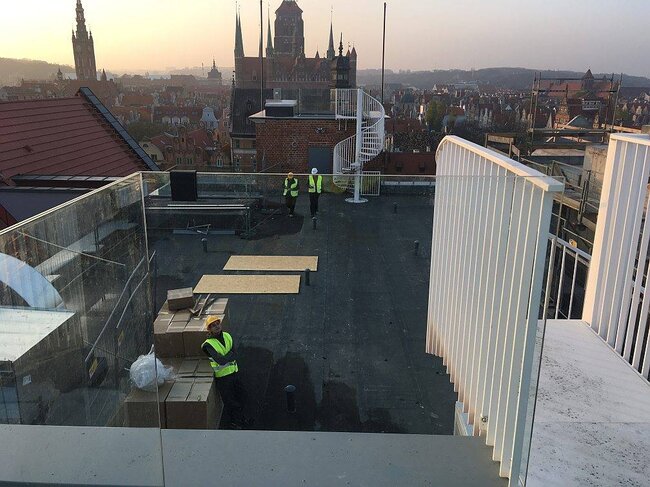 Flat roof deck surface undergoing preparation for an adjustable pedestal paving system.