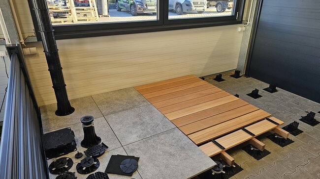 adjustable pedestals supporting pavers and a wooden deck pla
